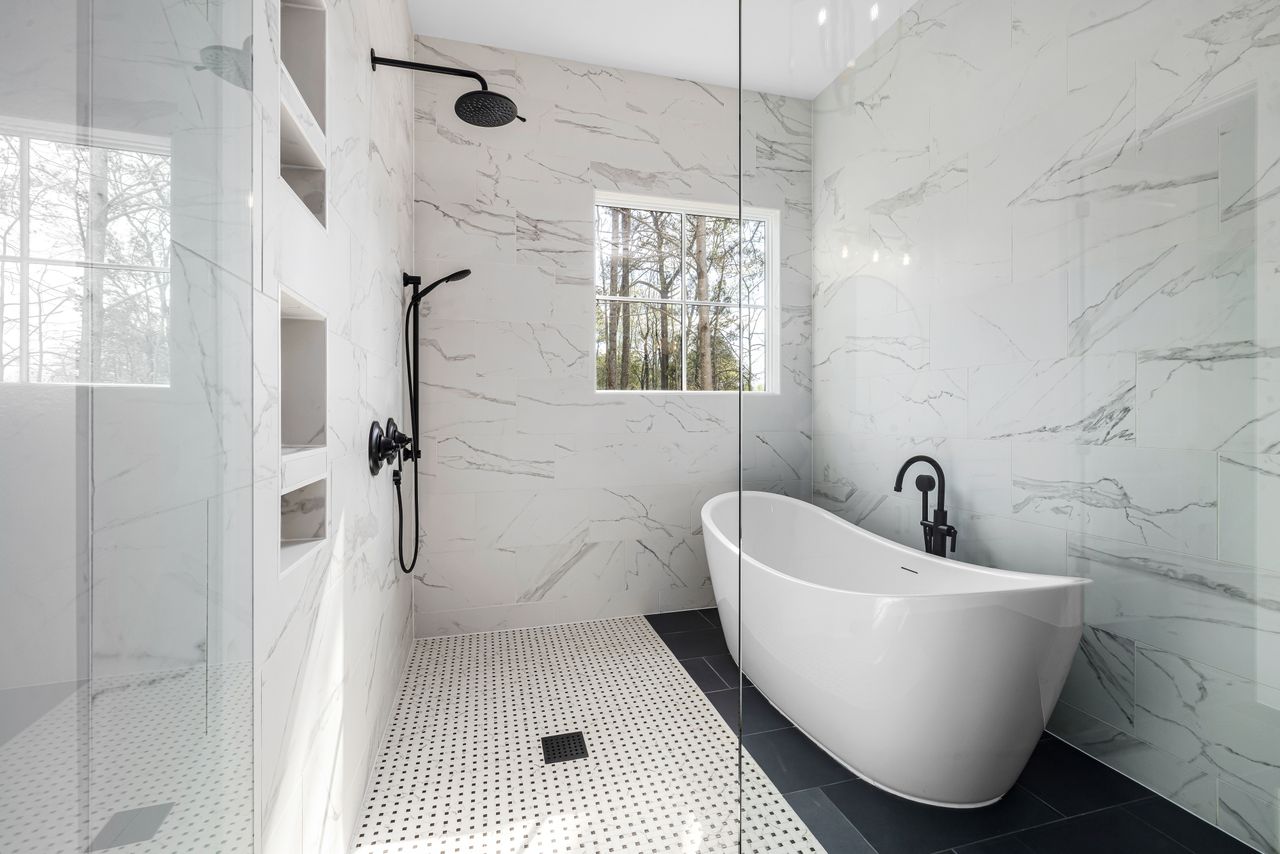 glass shower enclosure in a bright white bathroom with tub